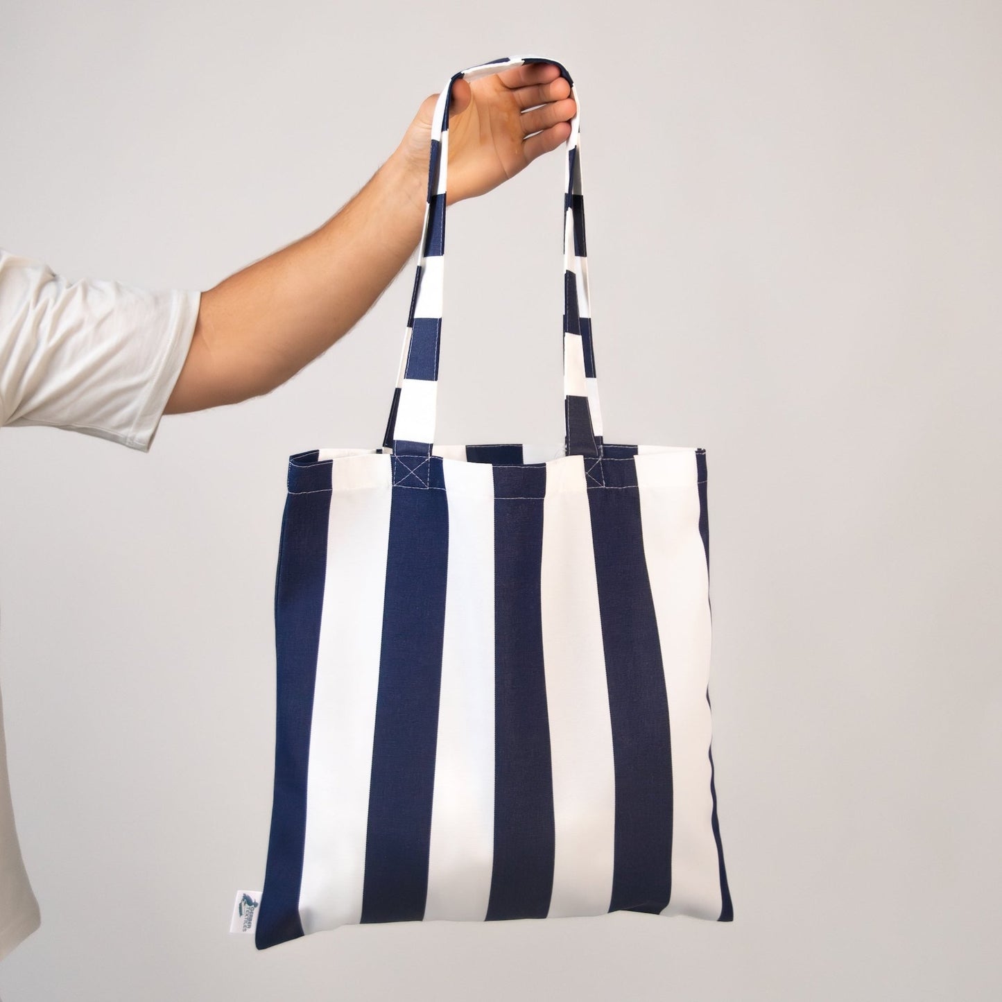 Hand holding Navy-and-white striped tote made from outdoor fabric.