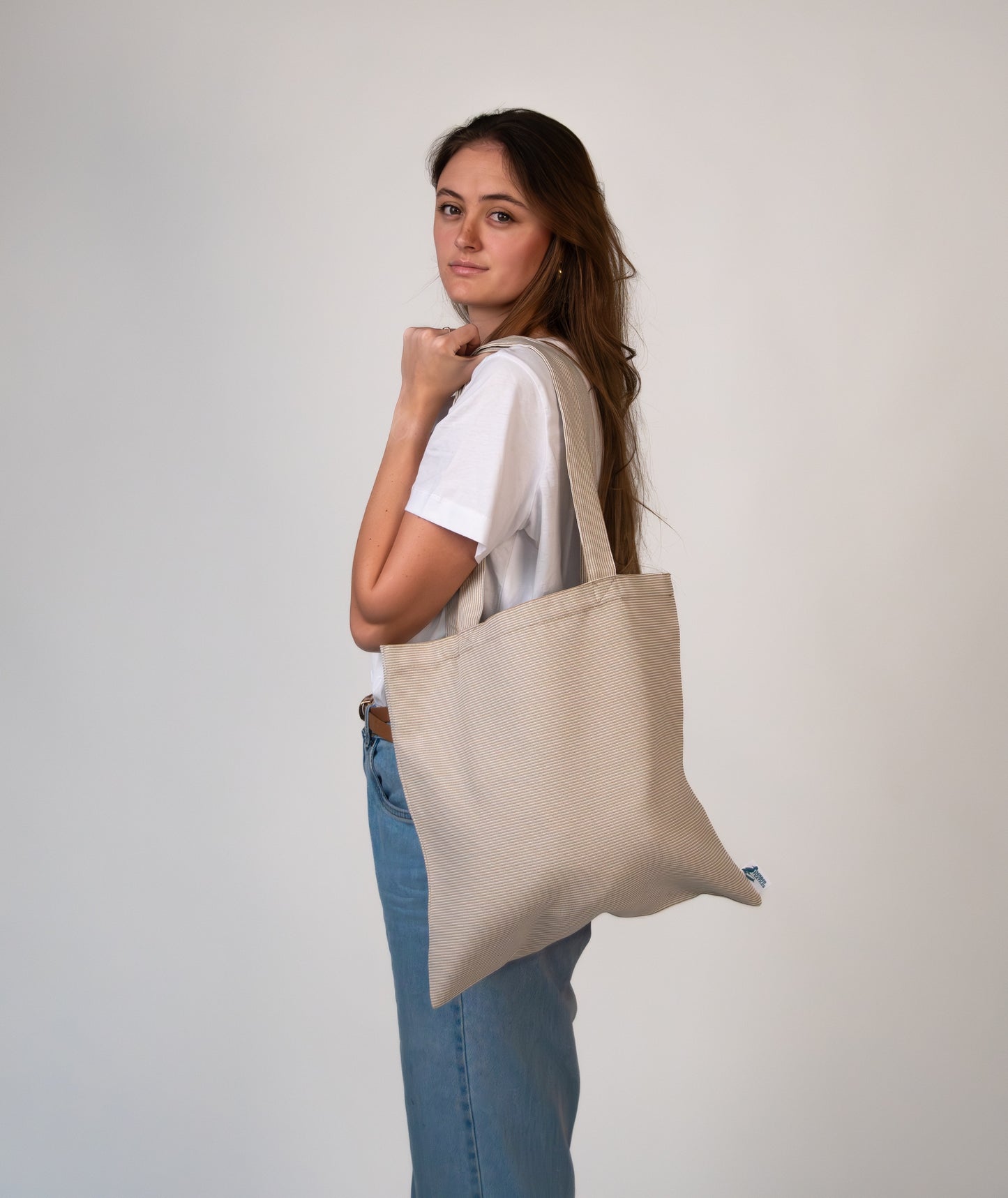 Female model carrying Agora Beige Tote Bag on shoulder – minimalist, UV-resistant design perfect for daily errands and travel.