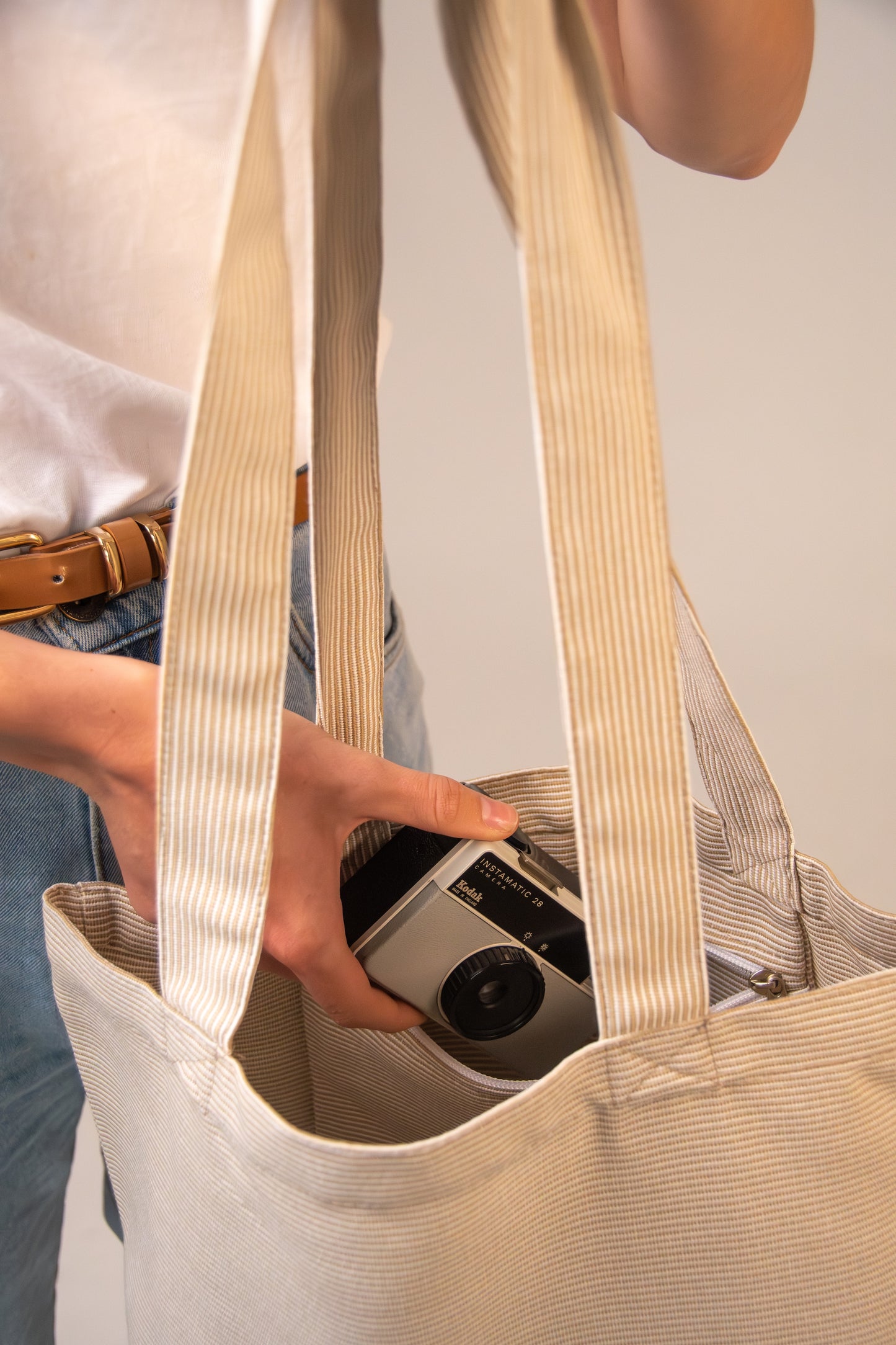 Close-up of Agora Beige Tote Bag interior showing secure zip pocket with a camera – durable, sand-resistant fabric ideal for storing valuables.