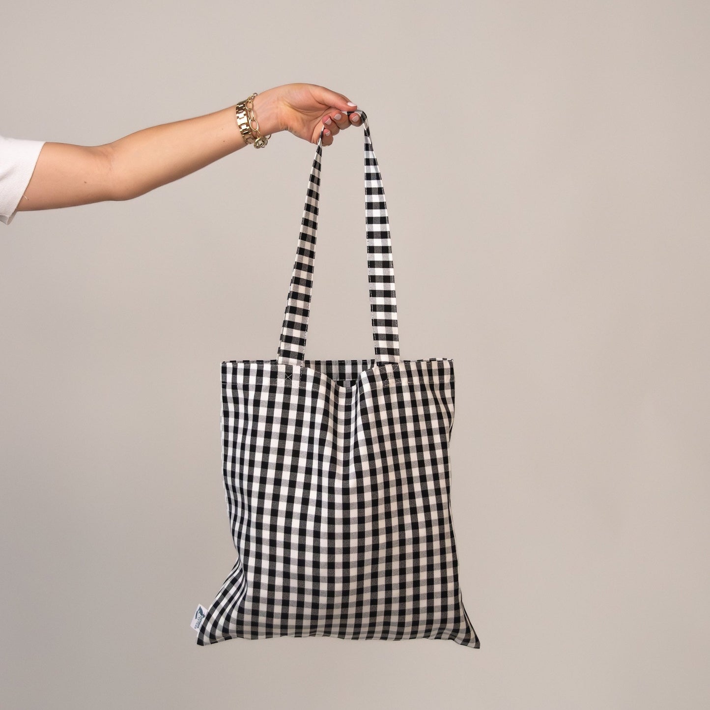 Hand holding black and white gingham Amalfi Jetset tote bag