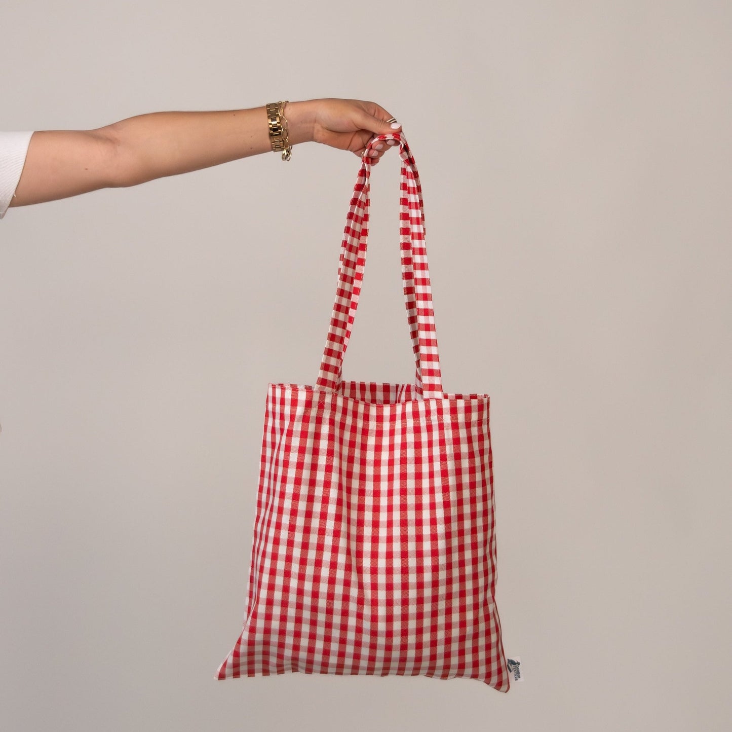 Hand holding Red and white gingham Amalfi red tote bag