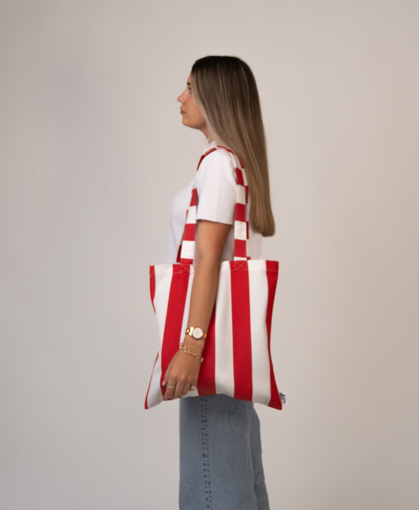 Woman wearing red striped tote over shoulder, showing scale.